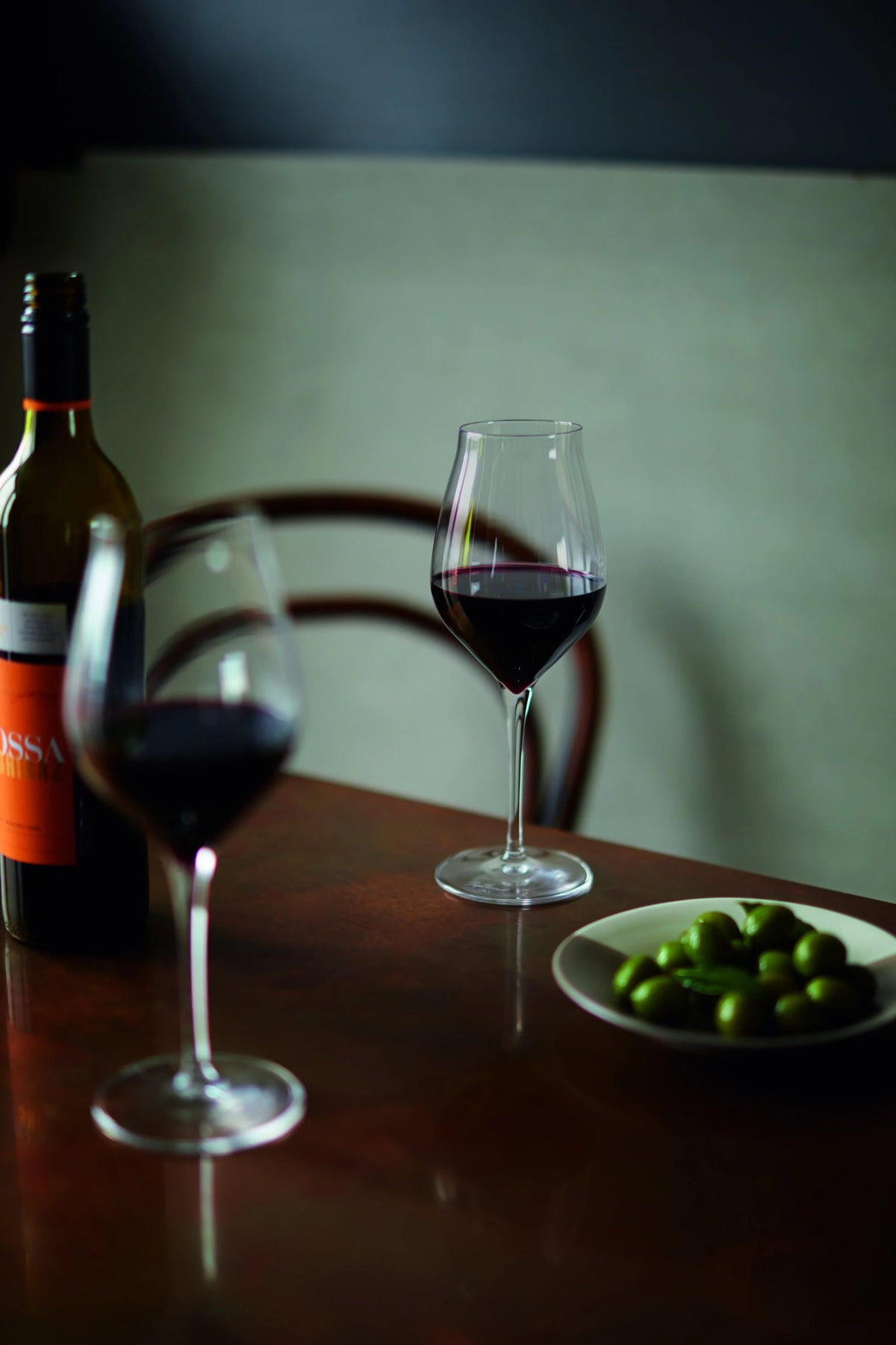 Food and prop styling for Waitrose by Ida Jacobsson-Wells, featuring red wine and olives in an atmospheric dining setting